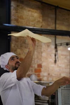 pizza chef tossing dough in traditional style